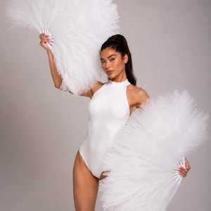 May include: A white high-neck bodysuit paired with two large, white, semi-circular hand fans constructed from layers of pleated tulle fabric. The fans feature a rigid white handle structure at the base, creating a voluminous, ruffled appearance.