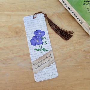 May include: A bookmark with a watercolour painting of purple flowers and green leaves. It has a brown tassel and a quote: "You have bewitched me body and soul." A copy of "Pride and Prejudice" is in the background.