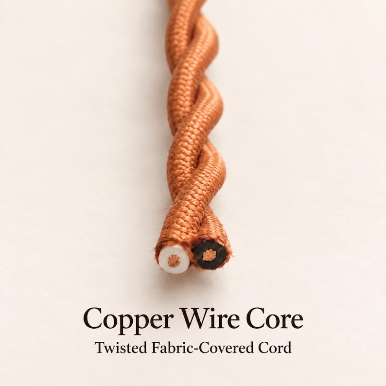 Close-up of a terracotta twisted fabric-covered pendant cord, showing two cut ends with black and white insulation surrounding stranded copper wire cores.