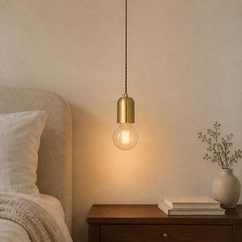 Style A plug-in bedside pendant with clear G95 globe bulb above a walnut nightstand in a warm neutral bedroom.