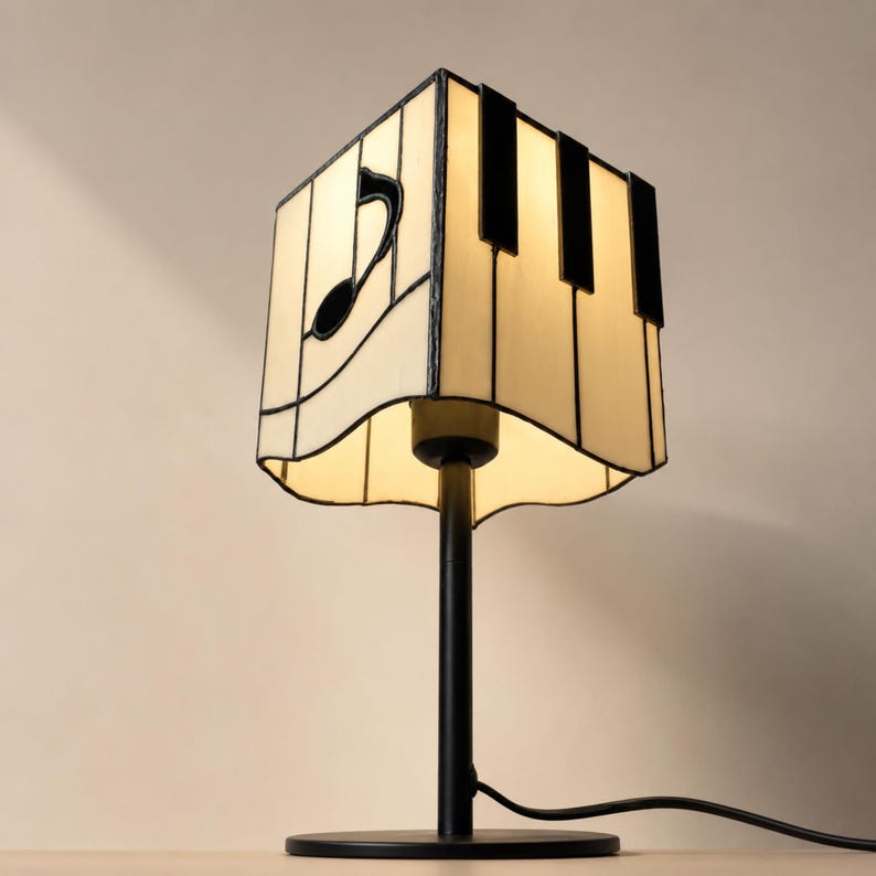 Low angle view of piano key and music note stained glass lampshade with warm light and black metal base