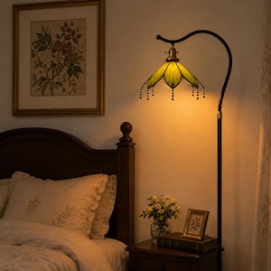 Handmade green stained glass floor lamp used as bedside lighting in a vintage botanical bedroom