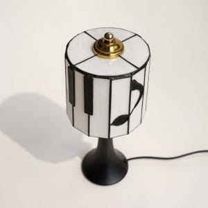 Top view of the piano stained glass lamp shade with brass finial and white glass panels.