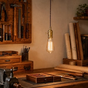 Style C antique brass rotary-key socket with clear ST64 Edison bulb hanging above a vintage woodworking bench.