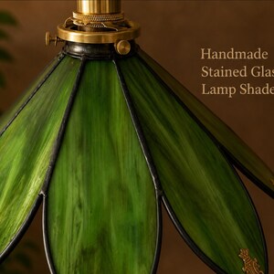 Close-up of handcrafted green stained glass lampshade with botanical leaf-inspired petals and decorative brass accents