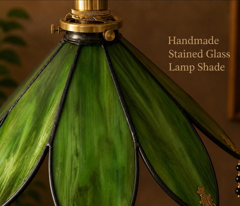 Close-up of handcrafted green stained glass lampshade with botanical leaf-inspired petals and decorative brass accents