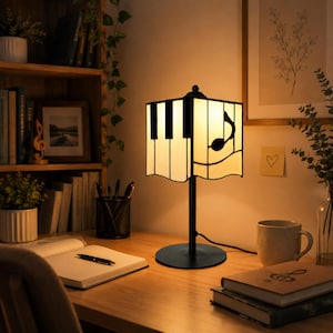 Piano stained glass table lamp with warm glow on a study desk beside sheet music and books
