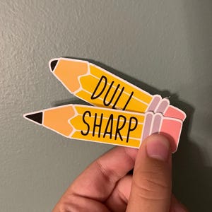 May include: Two yellow pencil-shaped stickers with black outlines. The top sticker says "DULL" and the bottom sticker says "SHARP".