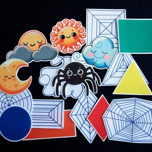 May include: A set of felt cutouts featuring a spider, sun, moon, clouds, and various geometric shapes. The shapes are outlined in black and some have a spiderweb pattern. The spider is black with white eyes and legs. The sun and moon are yellow with smiling faces. The clouds are gray with smiling faces. The geometric shapes include a triangle, square, rectangle, and diamond.
