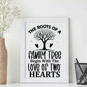 Peut inclure: Une impression encadrée blanche avec le texte "The Roots of a Family Tree Begin With The Love of Two Hearts." Un vase avec des fleurs blanches et un porte-stylo avec des stylos et une règle sont également dans l'image.