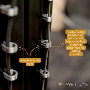 以下が含まれることがあります： 衝撃や衝撃に耐え、壊れないように設計された黒いケーブル管理クリップ。クリップは2つのサイズがあり、黒い表面に取り付けられています。画像の右下隅に「LAYER LUXE」というテキストが表示されています。