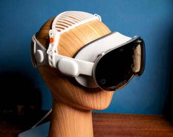 May include: White virtual reality headset with a white headband and a black lens. The headset is on a wooden mannequin head.
