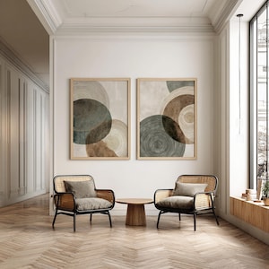 Puede incluir: Dos impresiones artísticas abstractas enmarcadas con diseños circulares en tonos marrón, verde y beige cuelgan sobre dos sillones negros con respaldos tejidos y cojines grises. Una pequeña mesa de madera se encuentra entre las sillas.