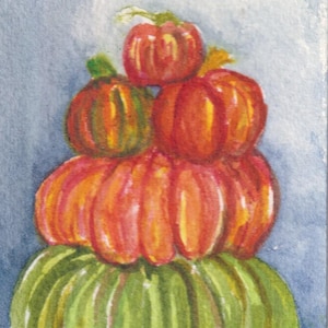 May include: A watercolor painting depicting a vertical stack of four pumpkins. The bottom pumpkin is large and green, topped by a medium orange pumpkin, a smaller orange pumpkin, and a tiny orange pumpkin at the peak. The initials SKF are visible.