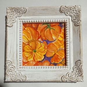 May include: A framed watercolor painting featuring vibrant orange and yellow flowers against a purple background. The artwork is encased in a distressed white wooden frame with ornate corner details, creating a rustic aesthetic.