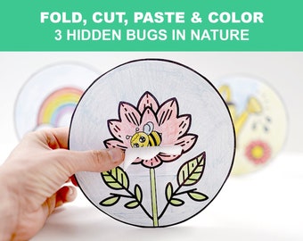 May include: A craft project featuring a circular paper design with a flower and bee illustration. The text "FOLD, CUT, PASTE & COLOR 3 HIDDEN BUGS IN NATURE" is at the top. The image is held by a hand, revealing a hidden bee.
