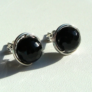 May include: A pair of silver wire wrapped earrings with black gemstone cabochons.