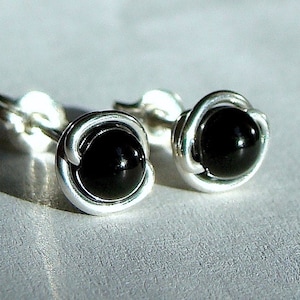 May include: A pair of silver earrings with black onyx stones. The stones are set in a simple, elegant design.
