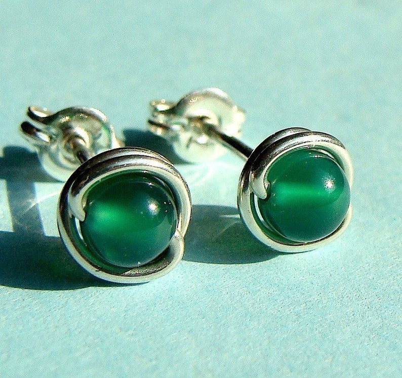 Peut inclure: Une paire de boucles d'oreilles en argent avec des pierres d'agate vertes. Les pierres sont serties dans une cage en fil de fer.