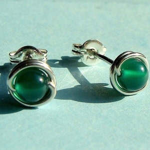 Peut inclure: Une paire de boucles d'oreilles en argent avec des accents de pierres pr&eacute;cieuses vertes. Les boucles d'oreilles sont faites avec un design en fil de fer.