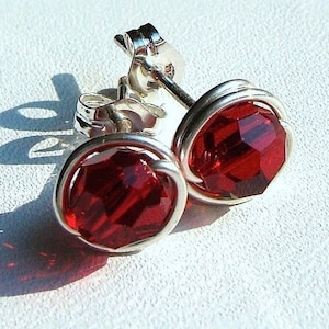 May include: A pair of silver wire wrapped earrings with red faceted glass stones.