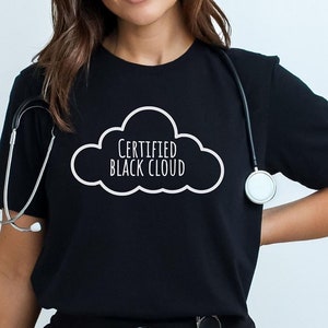 May include: Black t-shirt with a white cloud graphic and the text "Certified Black Cloud". The shirt is worn by a person with a stethoscope around their neck and a badge holder attached to their pants.