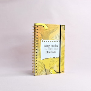 Side view of yellow, guided journal enhanced with gold binding, gold corners, elastic holder.