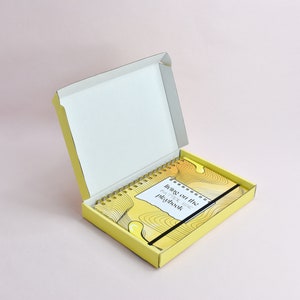 Yellow guided journal displayed inside of the custom yellow shipping box. Box is open, exterior yellow, interior white.