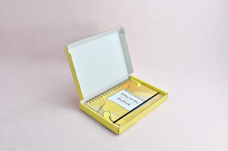Yellow guided journal displayed inside of the custom yellow shipping box. Box is open, exterior yellow, interior white.