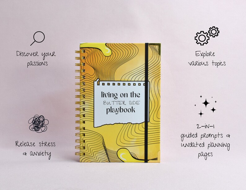 Front view of hard cover of a yellow, guided journal, gold binding, gold corners, elastic holder. Features captions that describe the benefits of the journal: release stress, discover passions, explore various topics, combined journal and planner.