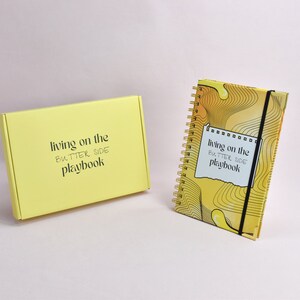 Front view of yellow guided journal, yellow, custom box. Journal enhanced with gold binding, gold corners, elastic holder.