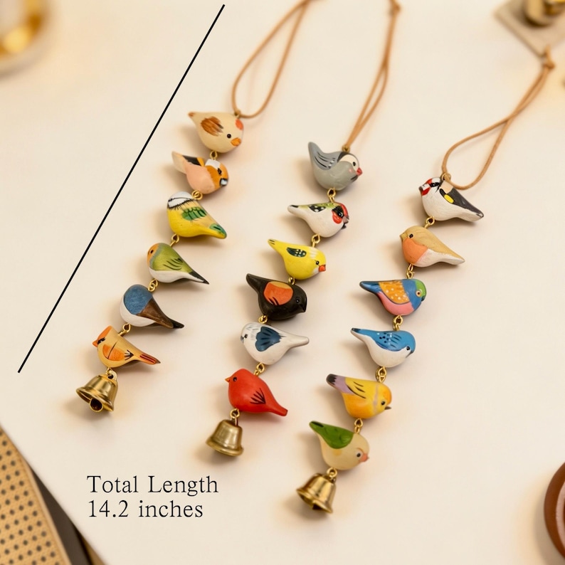 May include: A collection of colourful, hand-painted wooden bird ornaments, each suspended by a brown cord. Each bird is unique in colour and design, with a small gold bell at the bottom. The total length is 36 cm.