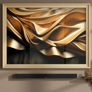 Può includere: Un'opera d'arte astratta incorniciata, con toni oro e neri, è appesa a una parete neutra. L'opera presenta forme fluide e strutturate. Sotto l'arte c'è una soundbar nera. In primo piano, una poltrona in pelle marrone.