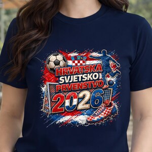 May include: Navy blue t-shirt with a soccer-themed graphic. The design includes a soccer ball, a player kicking a ball, a soccer shoe, and the text "HRVATSKA SVJETSKO PRVENSTVO 2026" in red, white, and blue.