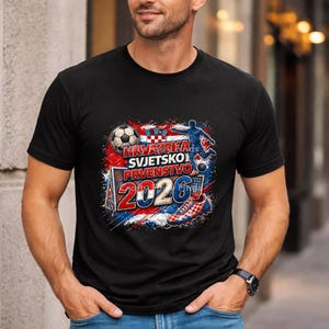 May include: Black t-shirt with a graphic design featuring a soccer ball, a soccer player, and the text "HRVATSKA SVJETSKO PRVENSTVO 2026" in red, white, and blue. The design incorporates the Croatian flag.