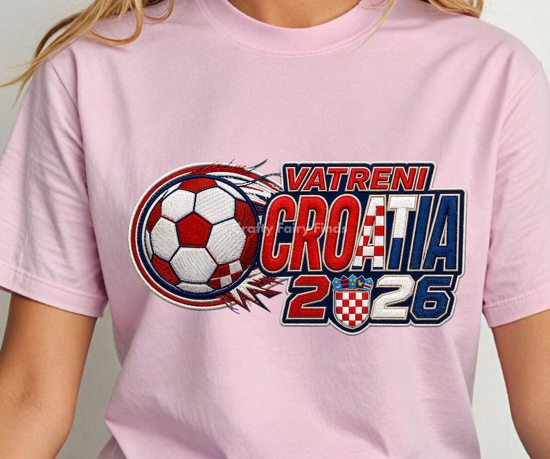 May include: A light pink t-shirt featuring a soccer ball design with red, white, and blue accents. The text "VATRENI CROATIA 2026" is displayed in a bold, stylized font, with a Croatian flag emblem.