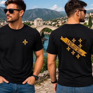 May include: A black short-sleeved t-shirt featuring a small yellow fleur-de-lis emblem on the front left chest. The back displays a yellow banner with the text I KRV SVOJU ZA BOSNU MOJU, surrounded by five yellow fleur-de-lis symbols on a black map.