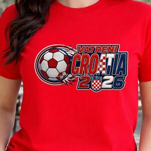 May include: Red t-shirt with a soccer ball graphic and the text "VATRENI CROATIA 2026". The design features the Croatian flag colors and a soccer ball with a fiery trail.