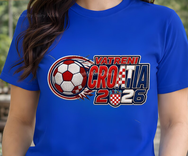 May include: A royal blue t-shirt featuring a soccer ball design with the text "VATRENI CROATIA 2026". The design includes the Croatian flag colors of red, white, and blue. The shirt is a crew neck style.