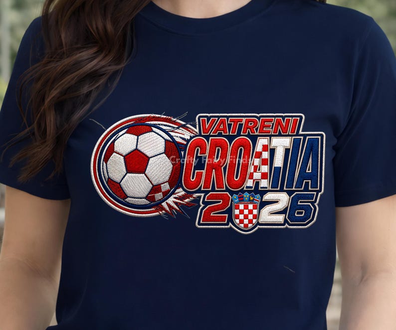 May include: Navy blue t-shirt featuring a soccer ball with red and white details, and the text "VATRENI CROATIA 2026". The design includes a Croatian flag emblem. The shirt is a sporty apparel item.