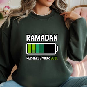 Unisex Ramadan “Recharge Your Soul” graphic shirt featuring a modern battery design symbolizing spiritual renewal. Handmade in the USA using durable DTF transfer. Available as t-shirt, long sleeve, or sweatshirt.