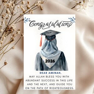 May include: A graduation card with the word "Congratulations" in elegant script. The card features a watercolor illustration of a graduate wearing a cap and gown, with the year 2026. The card includes a personalized message.
