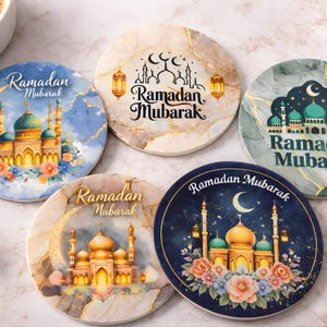 May include: Set of five round coasters with "Ramadan Mubarak" text and mosque illustrations. Designs include a crescent moon, lanterns, and floral accents. Colors include blue, gold, and marble patterns.