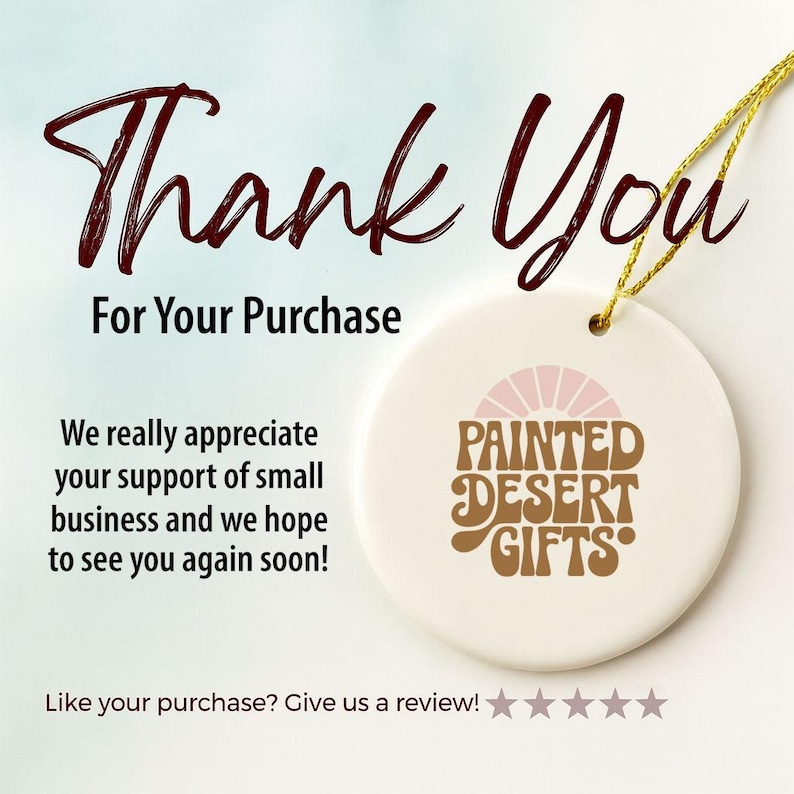 May include: A white ceramic ornament with a gold string, featuring the text "Thank You For Your Purchase." The ornament has a logo that says "Painted Desert Gifts" in brown and pink. The text "We really appreciate your support of small business" is also visible.