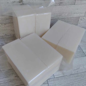 May include: Three white rectangular blocks of soap wrapped in clear plastic. The soap is stacked on top of each other.