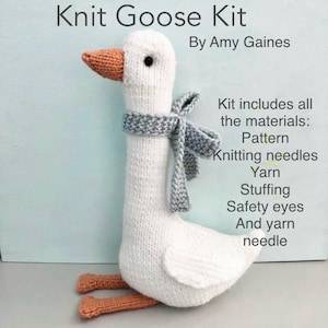 May include: A knitted goose kit with the text "Knit Goose Kit By Amy Gaines." The goose is white with an orange beak and feet, and a gray scarf. The kit includes pattern, needles, yarn, stuffing, safety eyes, and a yarn needle.