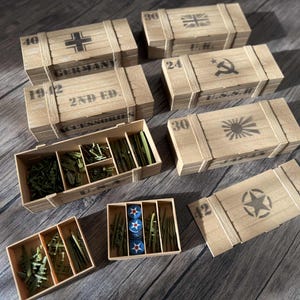May include: Wooden miniature crates with various military symbols and text, including a cross, hammer and sickle, rising sun, and star. Some crates are open, revealing miniature accessories.