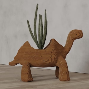 Puede incluir: Una maceta de madera con forma de tortuga con un cactus en su interior. La maceta está hecha de madera en capas, mostrando la veta natural de la madera. El cactus tiene múltiples tallos verdes. La tortuga tiene un cuello largo y cuatro patas.