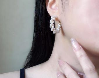 May include: A pair of gold hoop earrings with white pearl beads. The earrings are in the shape of a circle and are made of small, white pearls.