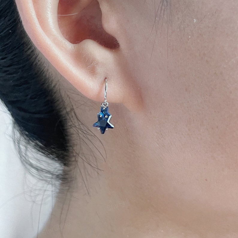 May include: A pair of silver star-shaped earrings with dark blue crystal accents.